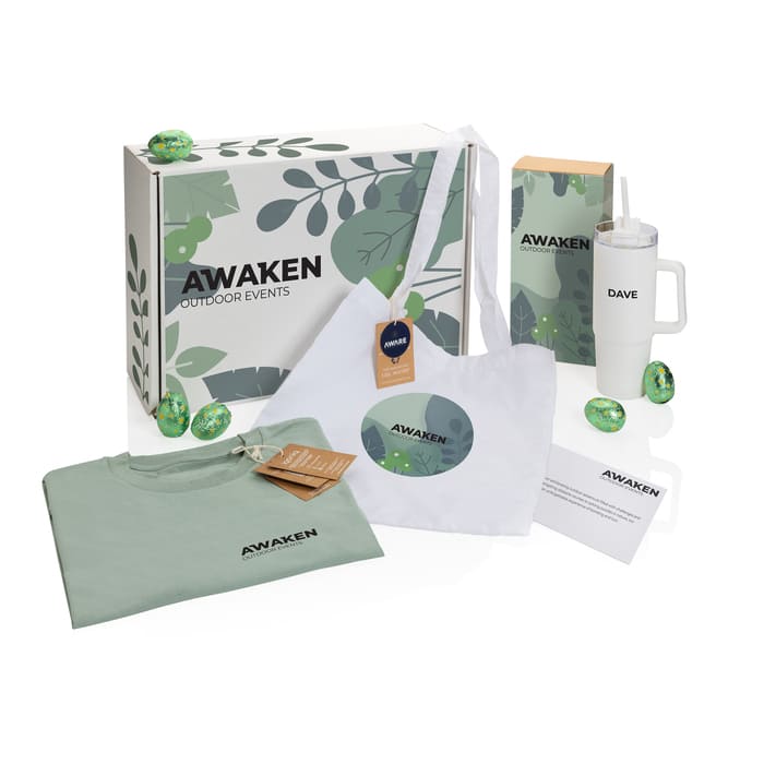 Kit de bienvenida ecológico para eventos al aire libre con bolsa de tela, taza térmica, camiseta y elementos naturales.